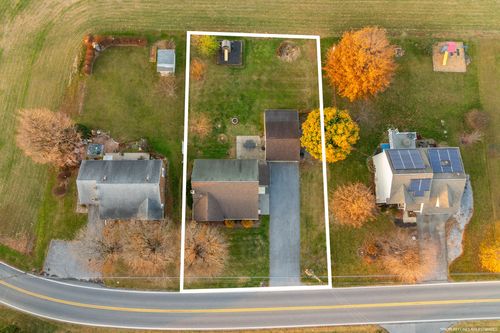 Aerial view of a suburban property with marked lot lines, driveway and fall foliage