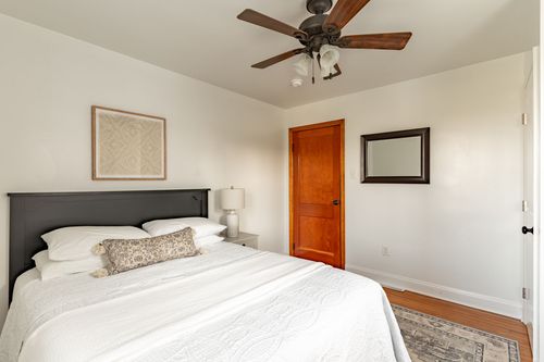 Bedroom with a black wood headboard, patterned throw pillow and a framed mirror on the wall