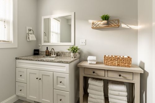 Bathroom vanity with granite counter, woven towel basket and a matching console table