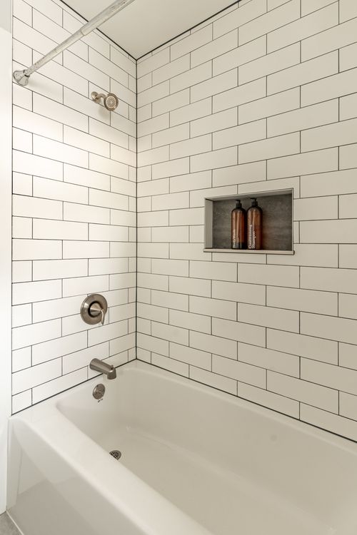 White subway-tile shower and tub with a built-in niche and brushed-nickel fixtures