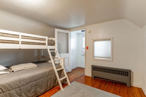 Loft bedroom with a white bunk bed, ladder and a wall-mounted radiator