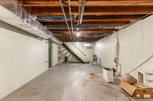 Unfinished basement with a wood staircase and exposed ceiling joists
