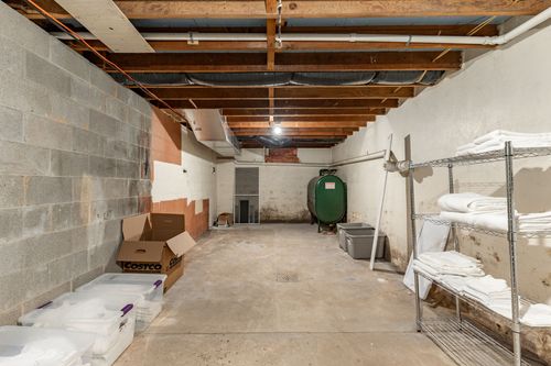 Basement storage room with wire shelving, folded linens and a green tank
