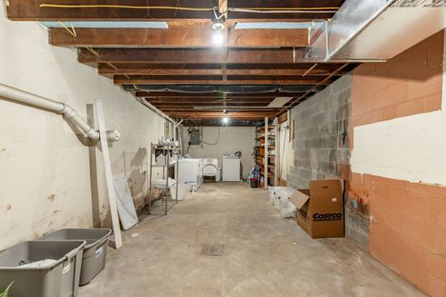Unfinished basement laundry area with washer and dryer beside block walls