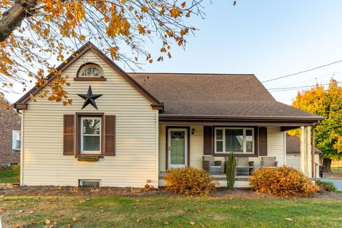 Close-up of a cape cod home's front gable with a star accent, shutters and porch furniture
