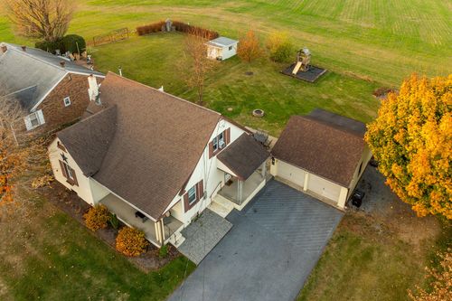 Aerial view of a cape-style home with an attached garage at autumn dusk