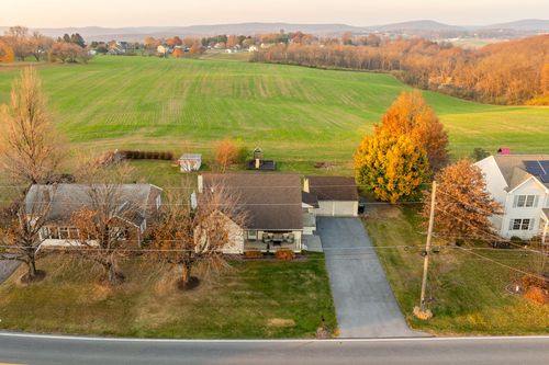 Aerial view of a farmhouse property surrounded by green fields at golden hour