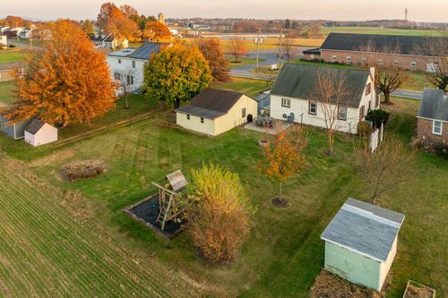 Aerial view of a white farmhouse and outbuildings amid autumn trees