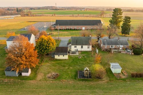Aerial view of a rural homestead near a large barn amid farmland at sunset