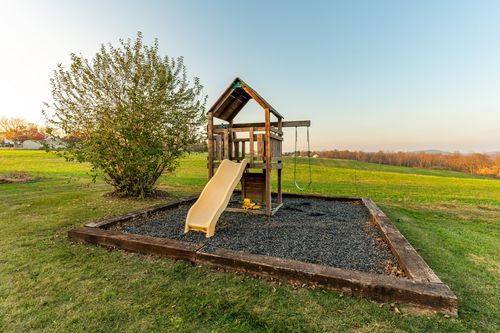 Wooden playset with a slide and swing set on a mulched play surface