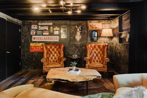 Rustic lounge corner with tufted camel-leather wingback chairs and a mounted animal head