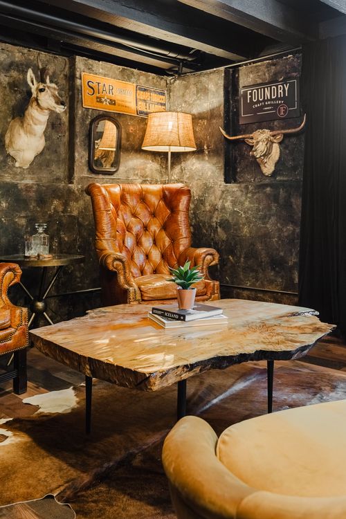 Tufted leather chair beside a live-edge table under a gold longhorn skull