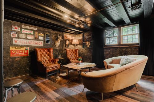 Lounge with tufted chairs, a curved sofa and a live-edge table under exposed beams