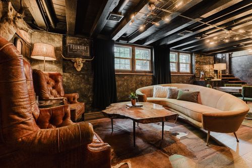 Cozy lounge corner with leather chairs, gold longhorn decor and a curved tan sofa