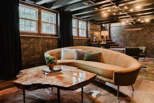 Curved tan velvet sofa with patterned throw pillows beside a live-edge coffee table