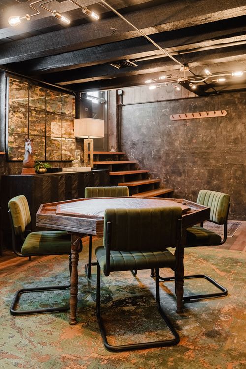 Octagonal poker table with green tufted chairs near a mirrored bar cabinet