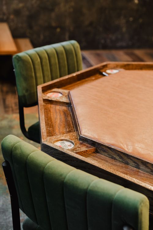 Close-up of an octagonal leather-top poker table with built-in drink holders