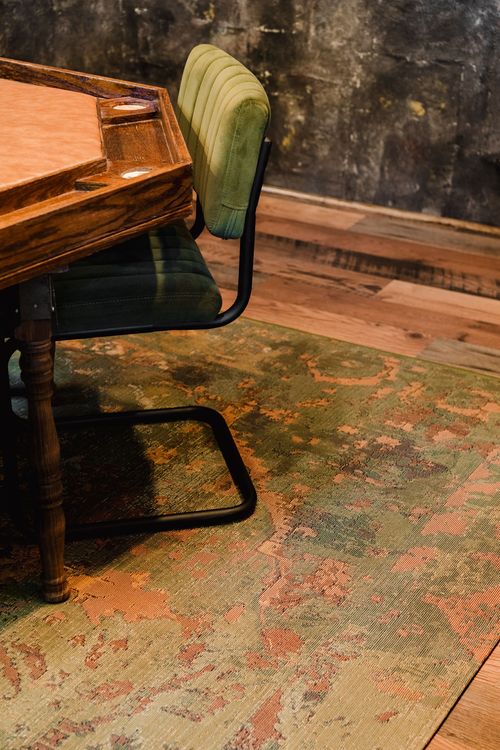 Detail of a wooden poker table corner with a cup holder and green velvet chair