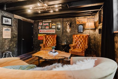 Industrial den with vintage advertising signs, leather wingbacks and a curved sofa