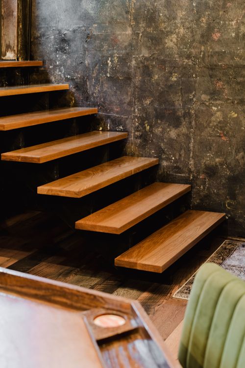 Floating oak stair treads set against a raw stone accent wall