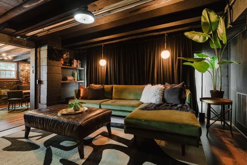 Cozy den with an olive velvet sectional, leather ottoman and globe pendant lights