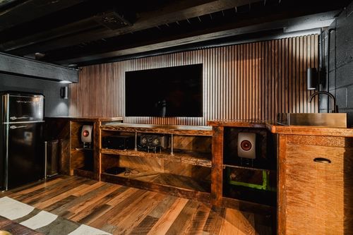 Media wall with a mounted TV set into corrugated metal paneling above a wood console