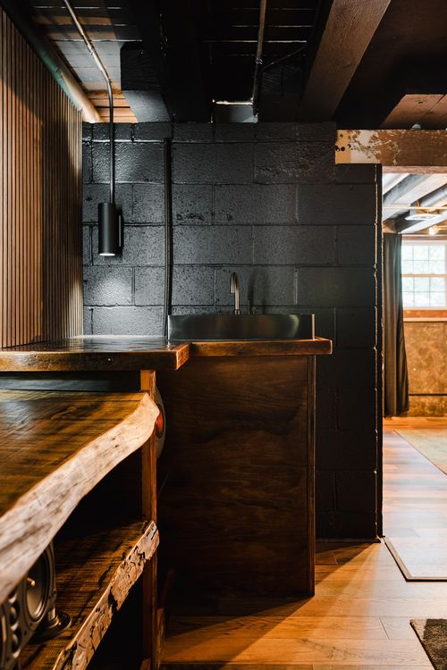 Dark wet-bar counter with a stainless sink against a painted block wall