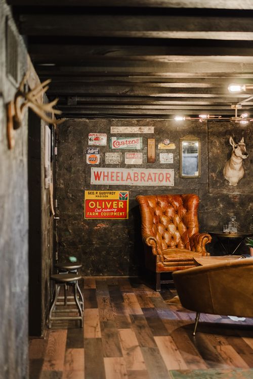 Antlers mounted on reclaimed wood beside leather chairs and vintage signage