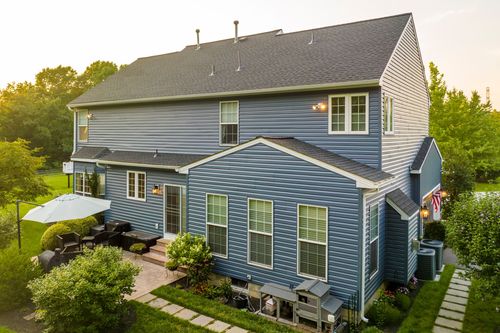 Aerial view of a blue home's rear patio with an umbrella table and seating