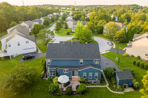 Aerial view of a blue home in a tree-lined suburban cul-de-sac
