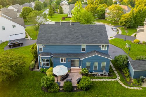 Aerial view of a blue two-story home with a patio, umbrella table and storage shed
