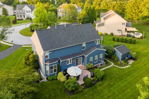 Aerial view of a blue home with cream accent siding beside a matching shed
