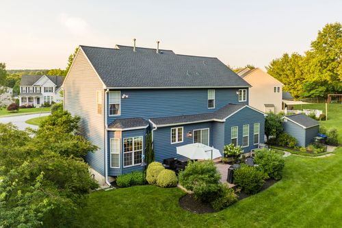 Aerial view of a blue colonial rear patio with umbrella seating and greenery