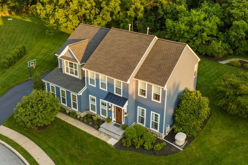 Aerial view of a two-story blue home with a stone gable and standing-seam entry roof