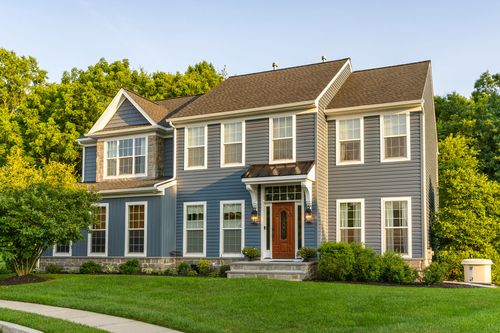 Front elevation of a two-tone blue and gray colonial with a wood door and stone steps