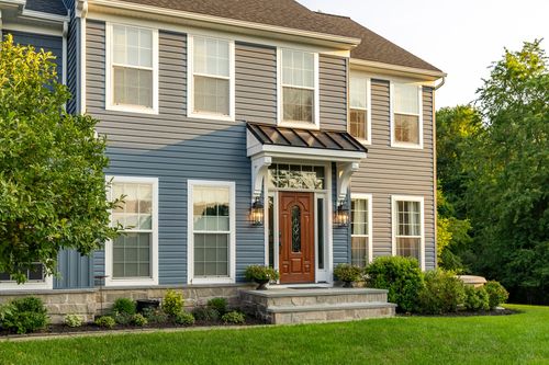 Front entrance detail of a blue home with a black standing-seam awning