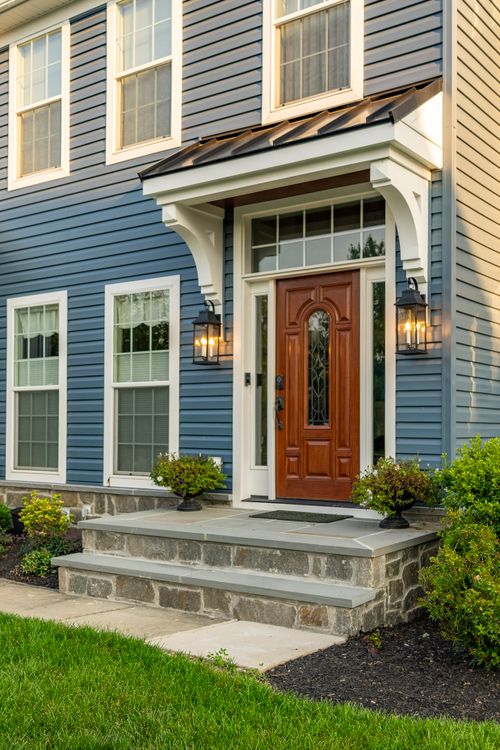 Close-up of a wood front door beneath a black standing-seam metal awning