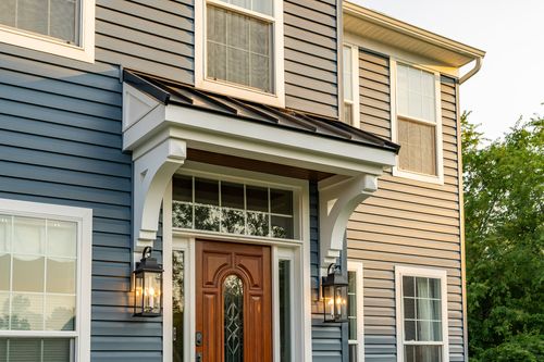 Wood front door with a black standing-seam awning on a two-tone home