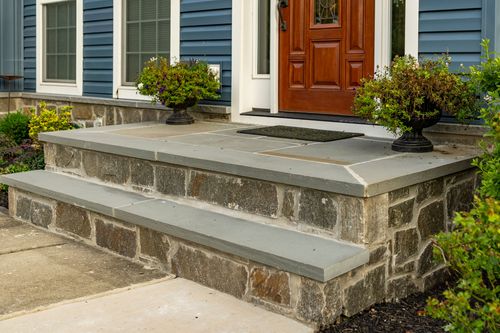 Stone entry steps with matching planted urns flanking a wood front door