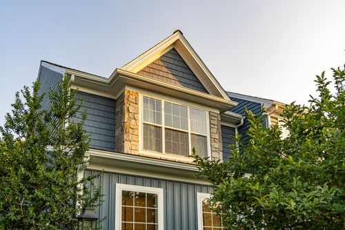 Close-up of a gabled dormer with a stone accent against blue-gray shingle siding