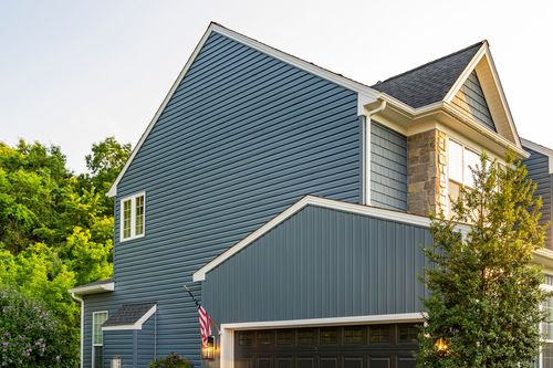 Close-up of a blue board-and-batten gable above a black garage door