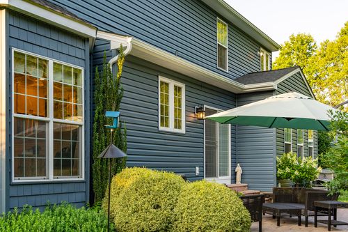 Patio corner with an umbrella table and a blue birdhouse post near the rear entrance