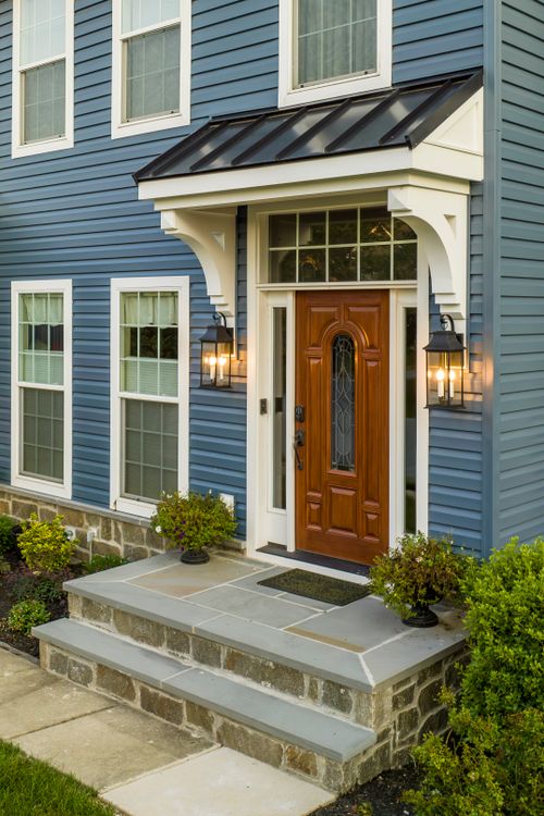 Covered front entry with a black metal roof, wood door and stone steps