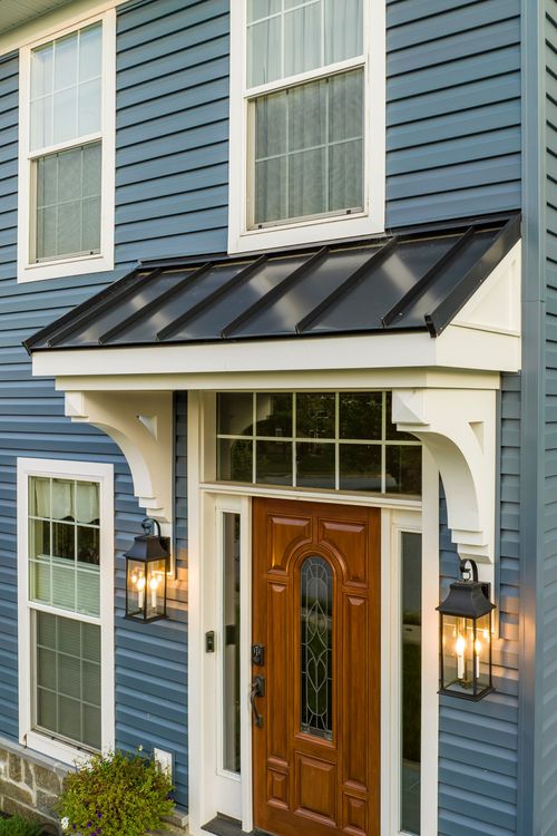 Close-up of a wood front door with sidelights framed by a white portico