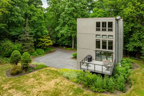 Aerial view of a gray modern home with a deck and circular gravel driveway