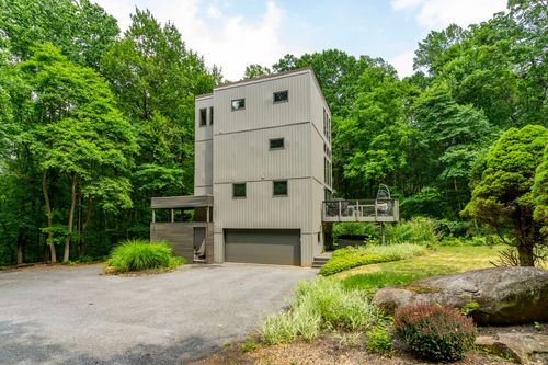 Contemporary vertical home with metal panel siding and an elevated deck among trees