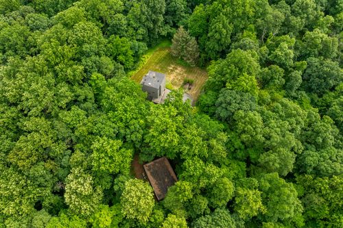 Aerial view of a modern home barely visible amid a dense green forest canopy