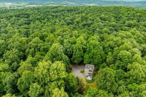 Aerial view of a modern home tucked deep within a vast wooded hillside