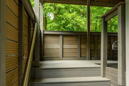Covered wood deck stairway with slatted privacy walls overlooking the forest