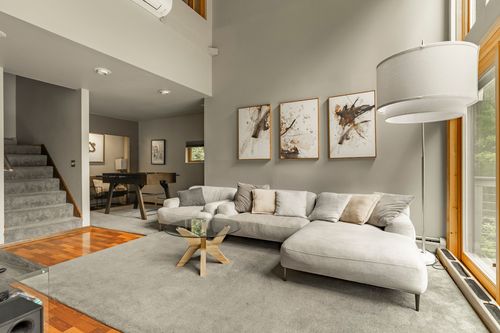 Open living room with wall-mounted TV, gallery wall art and hardwood floors near a staircase